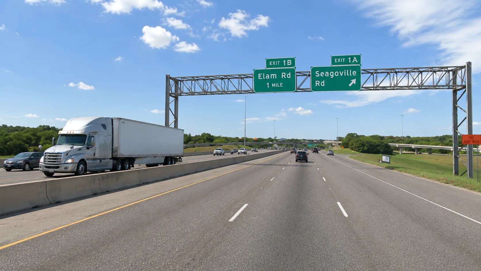 Interstate 635, the LBJ Freeway, through Balch Springs, Texas, with an 18-wheeler and passenger vehicles approaching the Elam Road and Seagoville Road exits under a partly cloudy Texas sky