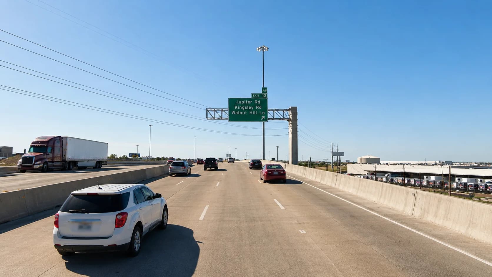 Interstate 635 through Garland, Texas, with an 18-wheeler and passenger vehicles approaching the Jupiter Road, Kingsley Road, and Walnut Hill Lane exit alongside a commercial trucking yard